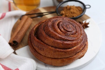Fototapeta premium Delicious cinnamon roll bun and spices on white table, closeup