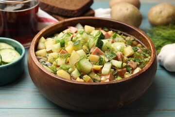 Delicious okroshka soup with kvass and ingredients on blue wooden table, closeup