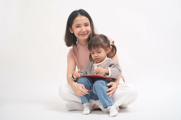 Young mother sits with her daughter, engaging with a tablet against a simple white background, showcasing a moment of family connection and digital learning.