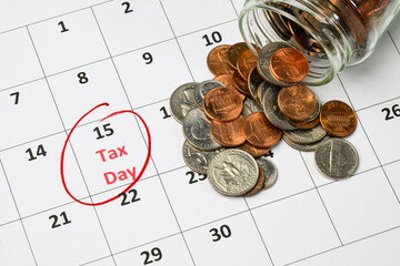 Jar of american coins spilled onto month calendar with Tax Day 15th circled in red ink