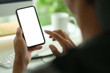 Close up young man holding mobile phone with blank screen sitting at modern office.