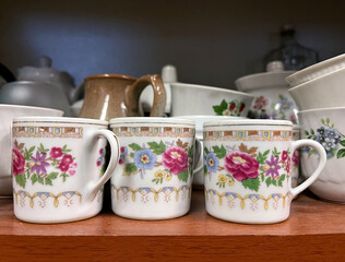 Antique Shop. Colorful floral soviet cups sit neatly on a wooden shelf surrounded by various...