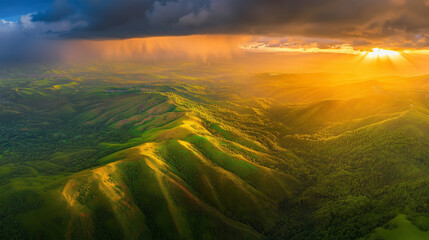 Aerial view of beautiful green hills and a dramatic cloudy sky at sunset, with the Cordillera mountain range near Trinidad in the background. The panoramic spring landscape features lush forests on th