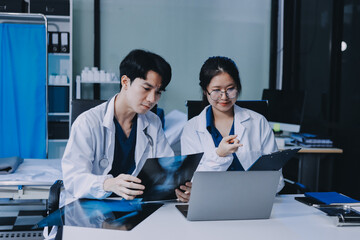 Positive doctor working on laptop in medical office, portrait.
