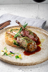 Grilled racks of lamb with demiglas sauce and vegetables on a plate. Main course of lamb on the bone, close up