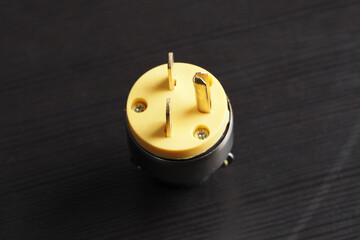 Electric plug socket with yellow base and metal connectors used for various electrical applications. Close-up.