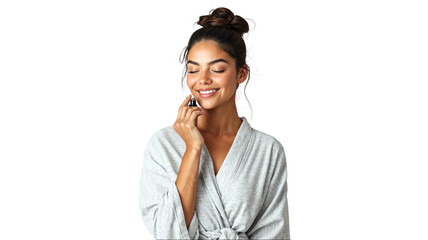  portrait of a young woman applying essential oils on her wrist as part of her wellness spa self-care routine, dressed in a light grey loungewear set, smiling with a sense of calm, isolated on a white