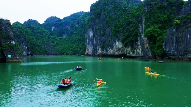 Aerial drone footage kayaking on the emerald waters of Halong Bay.