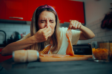 Cooking Woman Holding Meat Feeling Disgusted by Its Smell. Person feeling nauseated because of poultry meat gone bad at home 