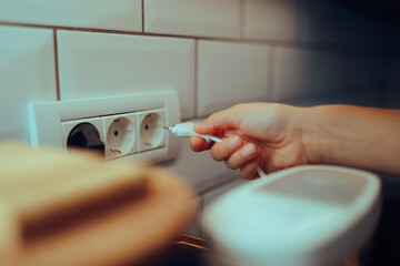 Unrecognizable person Puts a plug in a Kitchen Socket. Woman using electric appliance afterwards...