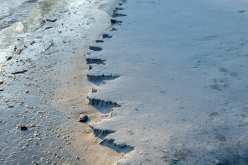 Frozen sand formations created by beach erosion along the shoreline in winter. 