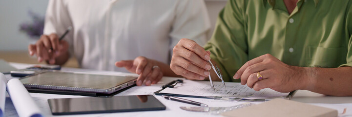Engineers pointing at architectural drawings and discussing the details of material requirements