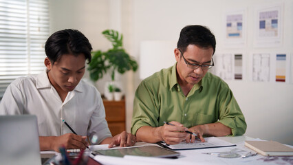 Engineering professionals calculating material quantities for a construction project using laptops and notepads.