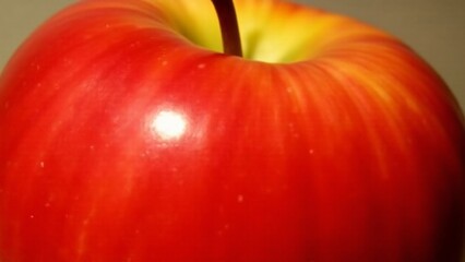 A close-up of an apple's smooth, glossy surface with a mirror-like finish. Lighting highlights its polished and flawless texture.