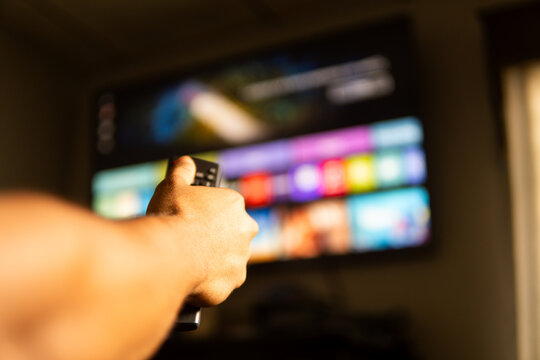 Person choosing streaming platform on smart tv using remote control