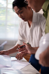 Engineers working together on construction project calculations, using blueprints, laptops, and technical tools at the meeting table