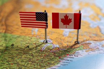 United States and Canada flags placed on a map, representing the close relationship and shared...