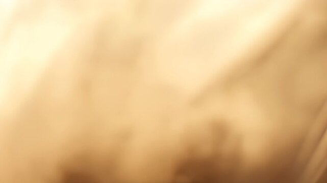 Soft golden fabric draping elegantly in a warm, serene setting, creating a tranquil atmosphere