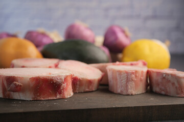 Freshly cut meat surrounded by colorful vegetables on a wooden board