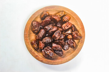 dates in a wooden bowl on a white background