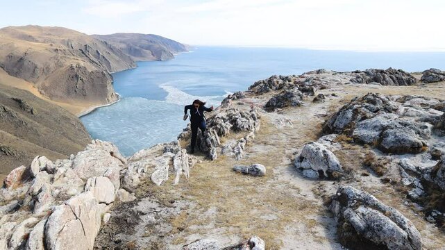 A young woman is hiking. A place to rest with a beautiful view of the spring lake and mountain landscape.