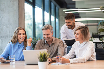 Successful businesspeople working in a coworking space working with laptop discussing strategy and...