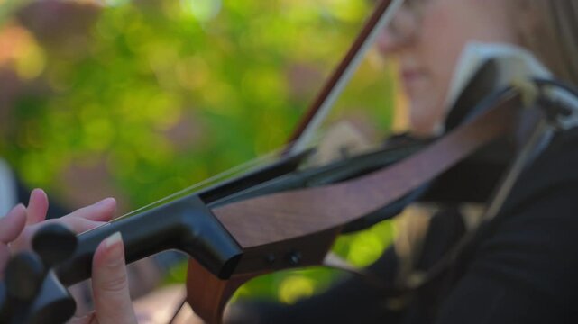 Musical violinist playing outdoor on sunny day. Close up