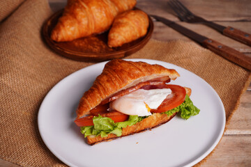 Croissant bread and poached eggs, vegetables and ham Breakfast on the table
