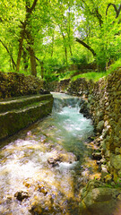 A vibrant water-filled valley surrounded by lush greenery and stone walls, showcasing the raw beauty of untouched nature.  
📍Masrachi, Kamalla 