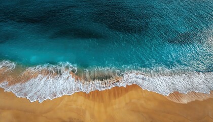 aerial view of clear turquoise ocean waves breaking on golden sandy beach with footprints on the shore