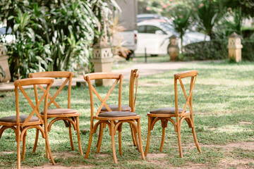 Five brown wooden chairs are placed on the grass in the garden