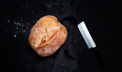 Homemade whole grain freshly baked bread. Black background, top view