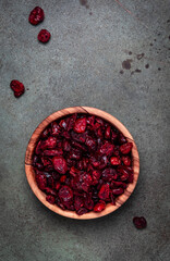 Organic sun dried cranberries in wooden bowl on green background, top view