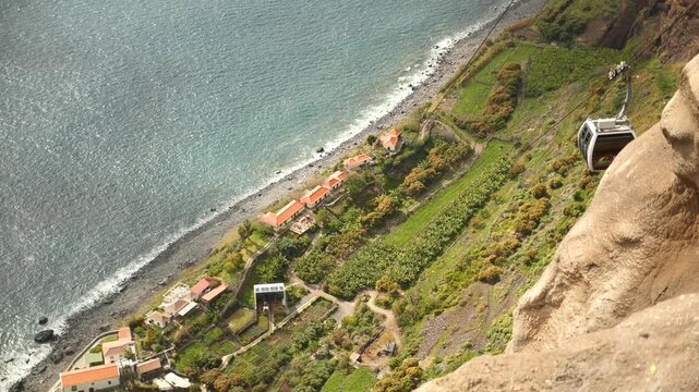 Spectacular viewpoint of a small village near the beach in Madeira, Portugal. View from above of a village near the ocean. Achadas da cruz cable car. High quality 4k footage