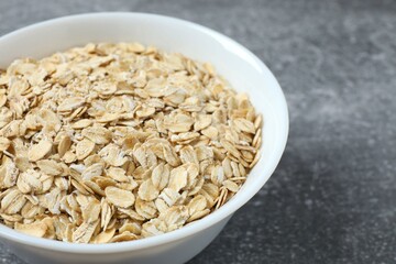 Composition with oatmeal flakes on gray background. Cooking breakfast