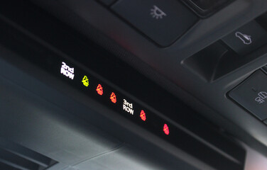 Illuminated seat belt indicators and sunroof controls on the ceiling panel of a large family car. Comfort and safety sensors inside car
