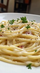 Close-up view of a delicious spaghetti dish with creamy sauce and fresh herbs served on a white plate