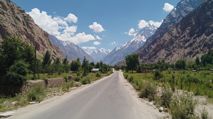 Fototapeta premium Mountain Road Through Valley with Snow-Capped Peaks