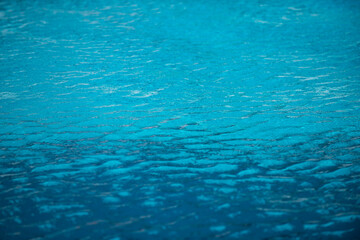 Blue pool water background. Blurred transparent clear calm water surface texture. Water waves in sunlight with copy space.