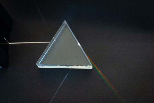 A beam of light is refracted in a triangular piece of glass creating a spectrum of colors. Experiment in physics class.