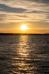 Obraz premium Beautiful golden sunrise over a calm sea with distant horizon. Peaceful sunrise scene with the sun reflecting on calm water. Early morning at bay
