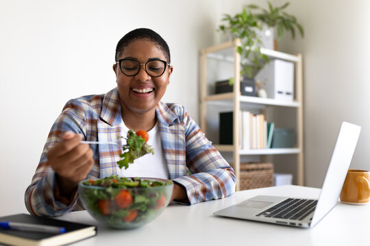 Happy manager eating fresh salad during work break at home office