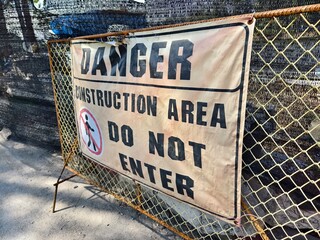 There is a noticeable sign warning of danger in front of the entrance to the construction site