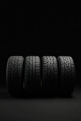 Obraz premium A quartet of new vehicle tires arranged in a row against a dark background. The various tread patterns are clearly visible.