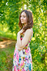 Fototapeta premium A beautiful girl in a bright dress walks in the park in summer in sunny weather.
