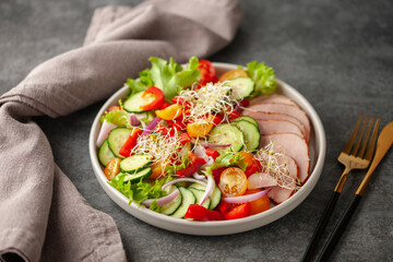 Vegetable salad with sliced meat in a plate on the table.
