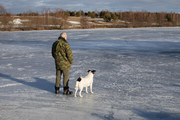 A man with a dog on the ice of a frozen dam
