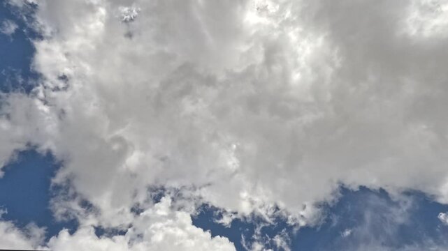 4K Timelapse of clouds passing overhead, with beautiful sunlight filtering through the top of screen.