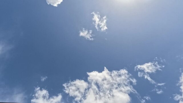 4K Timelapse of clouds passing overhead, with beautiful sunlight filtering through the top of screen.