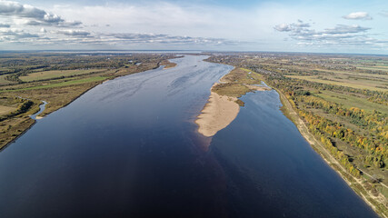 Large body of water with a shoreline and a few small islands. Golden colors of a beautiful September forest